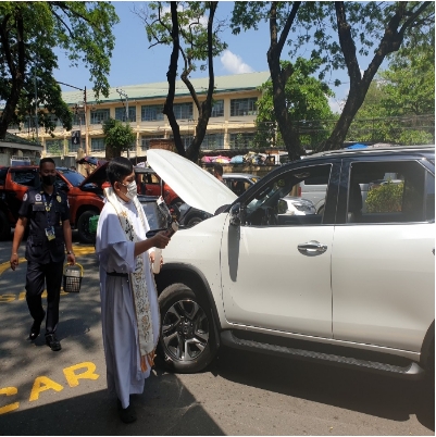대기 중인 차량에 성수를 뿌리며 축복하는 사제 - 출처: 통신원 촬영